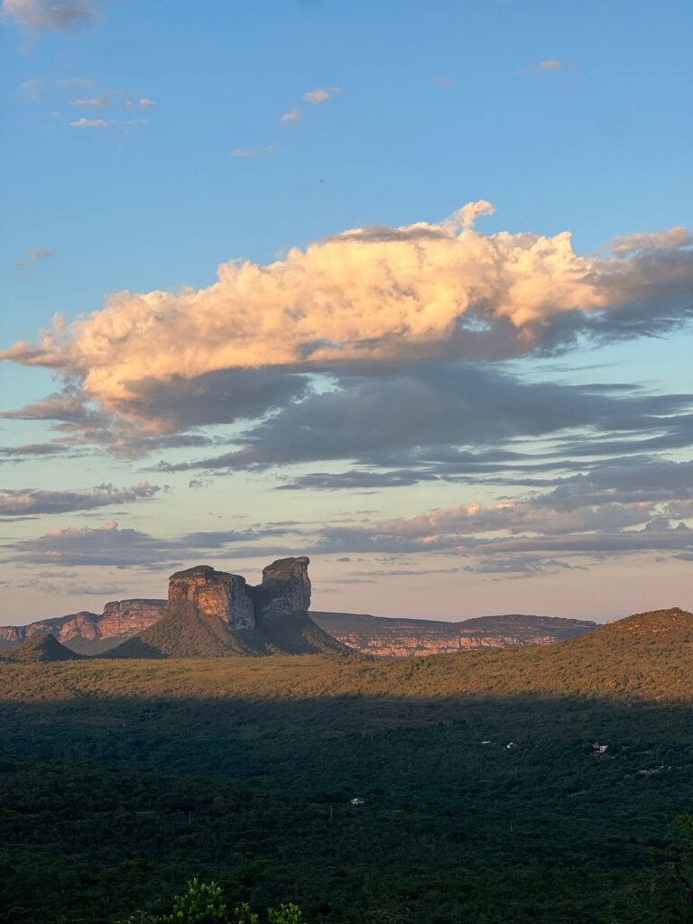 Pôr do sol com nuvens dramáticas sobre terreno verde de chapada